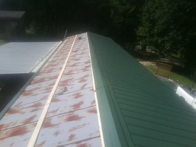 Old rusted panels beside newly installed green metal roofing — Wind Damage Roof Repair by Roofing Brothers in Reedsburg