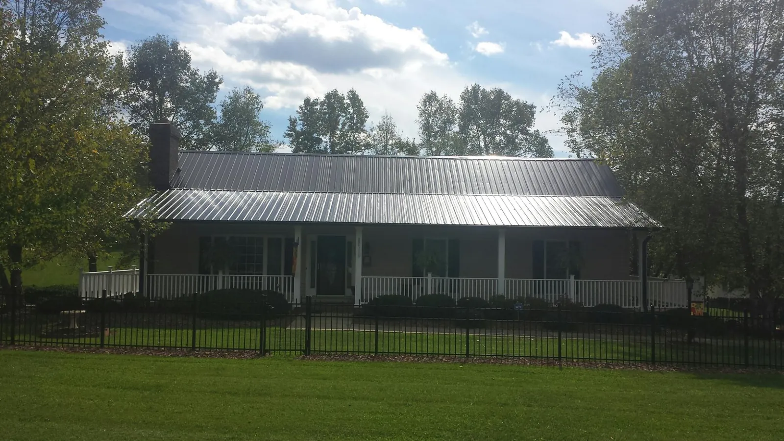 Gray metal roof on a brick ranch with a full width front porch — Gutter Guard Installation work by our crew in Reedsburg