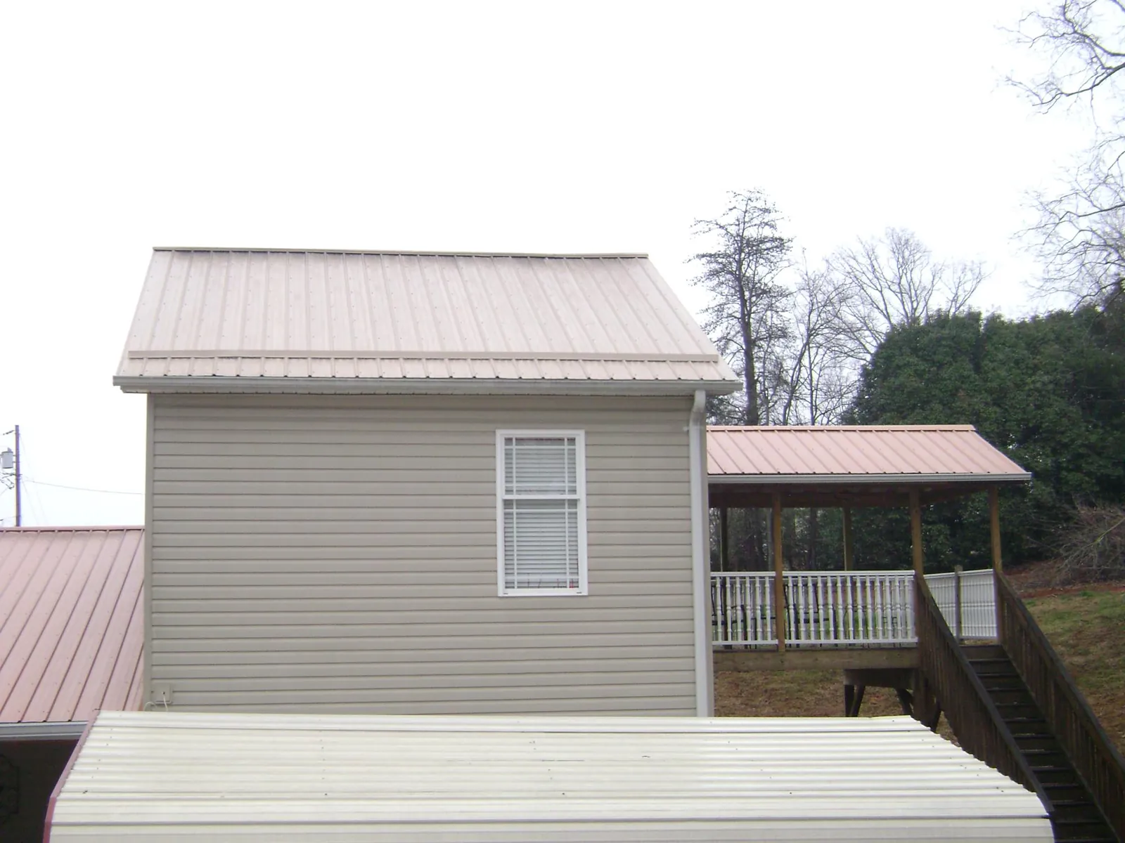Tan metal roofs on a two story addition and attached porch, from a Roof Replacement job in Reedsburg