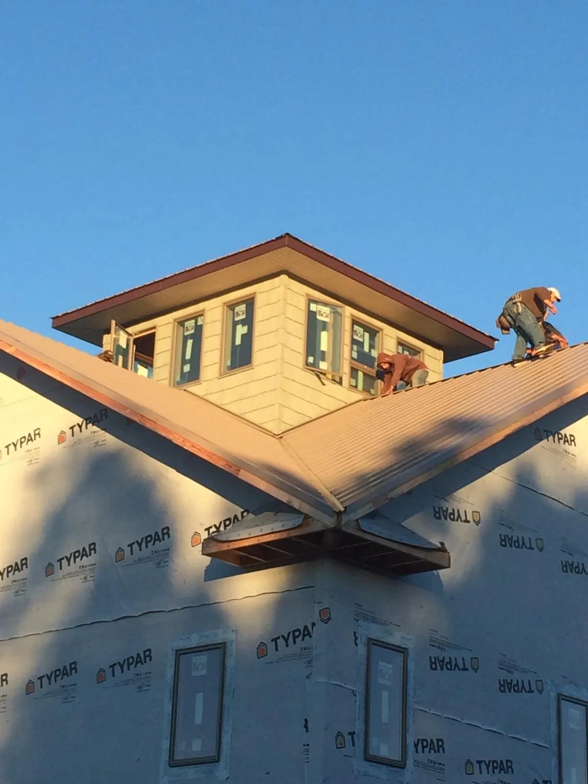Roofers working around a rooftop cupola on a new metal roof at sunset — Roof Waterproofing in Reedsburg by Roofing Brothers